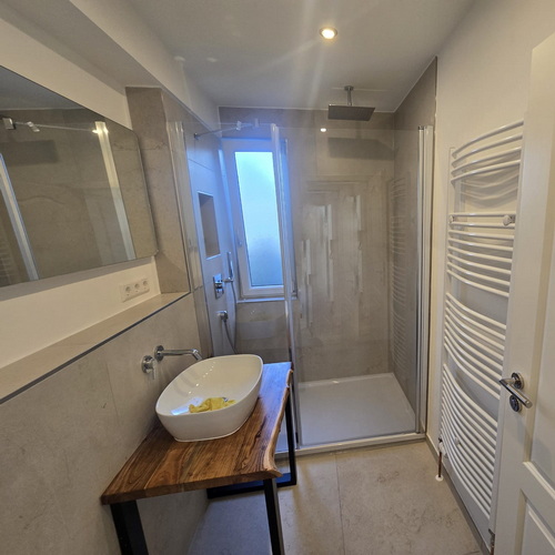 Sanierte Dusche mit rahmenloser Duschkabine im modernen Badezimmer